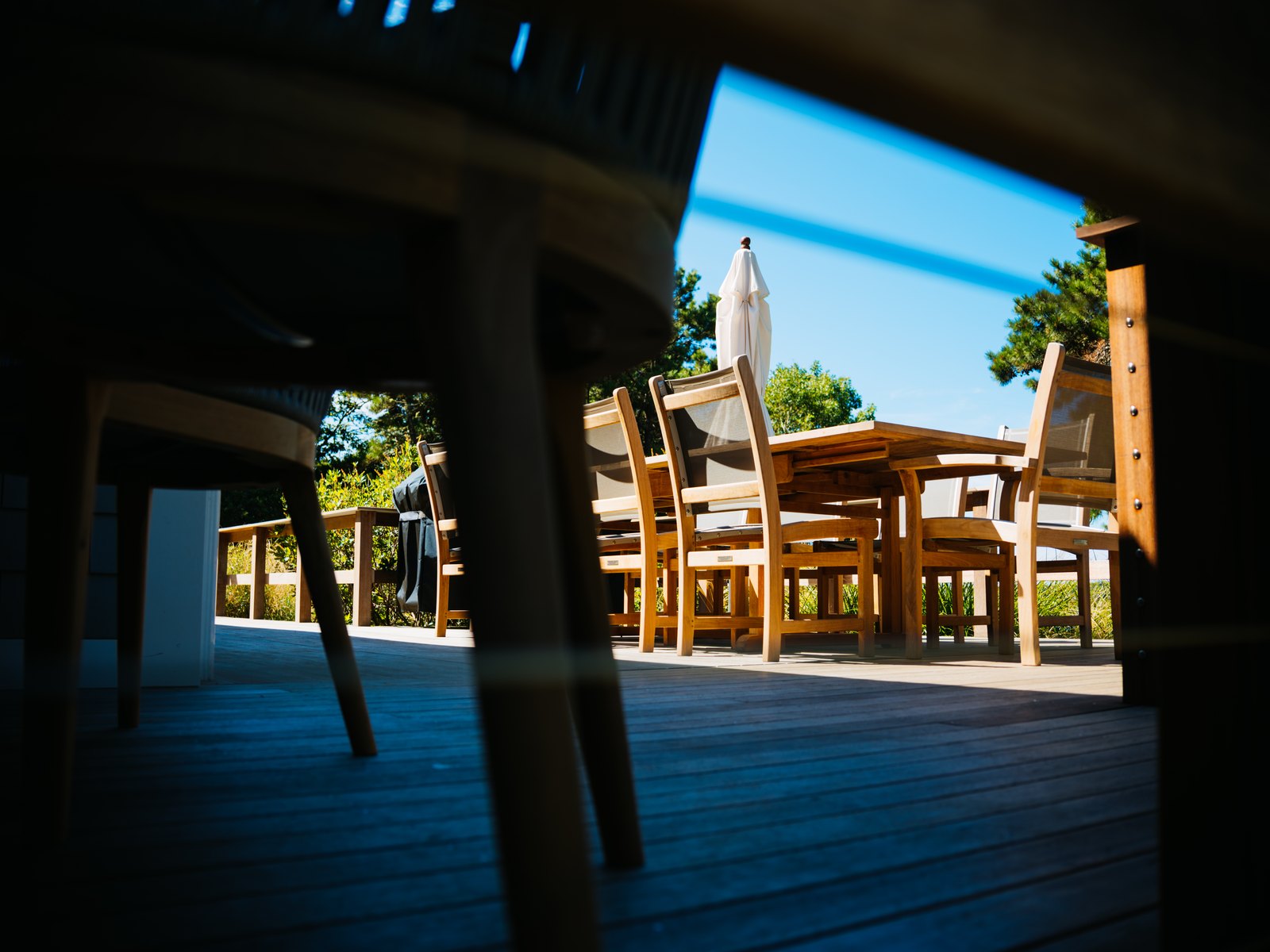 Caleb's Pond House — the deck seen past the dining table, chairs and umbrella beyond