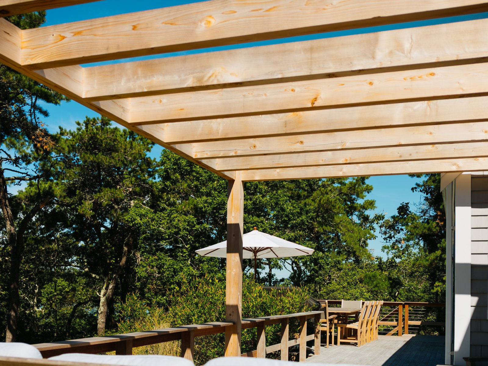 Caleb's Pond House — the pine trellis over the deck, and the trees past it