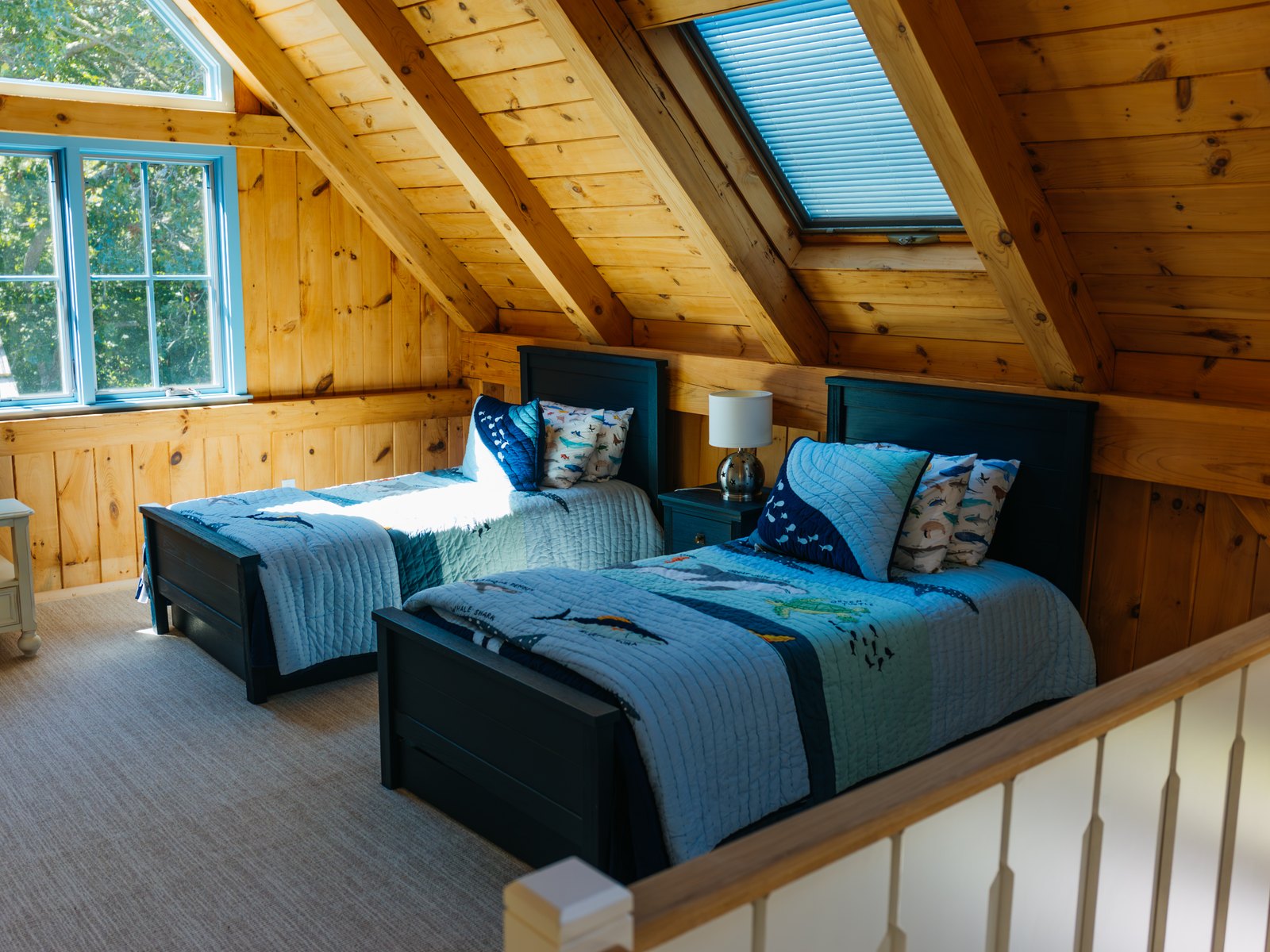 Caleb's Pond House — a bedroom set under the pine rafters, with a skylight above